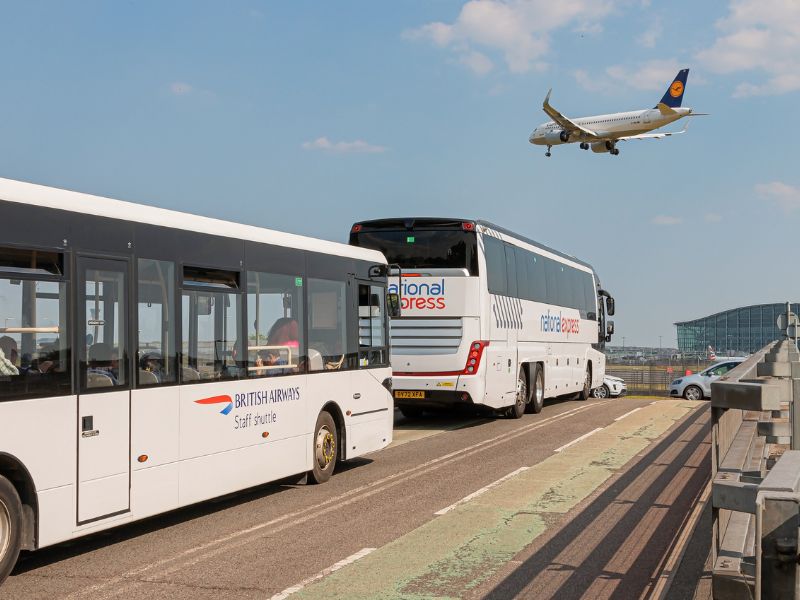 Flughafenshuttlebus von National Express in London mit Flugzeug im Hintergrund